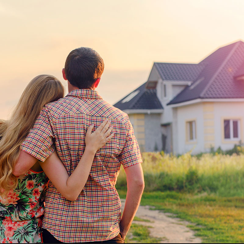 Glückliches Paar steht vor Ihrem Traumhaus